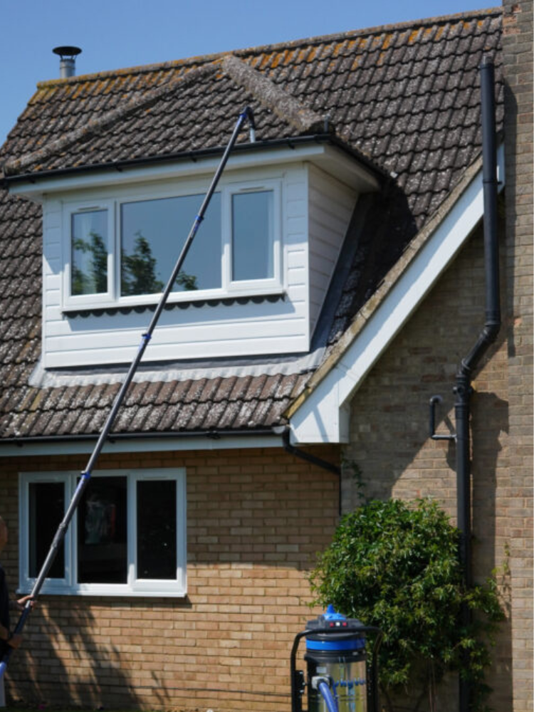 A gutter vacuum pole reaching the guttering of a brick house