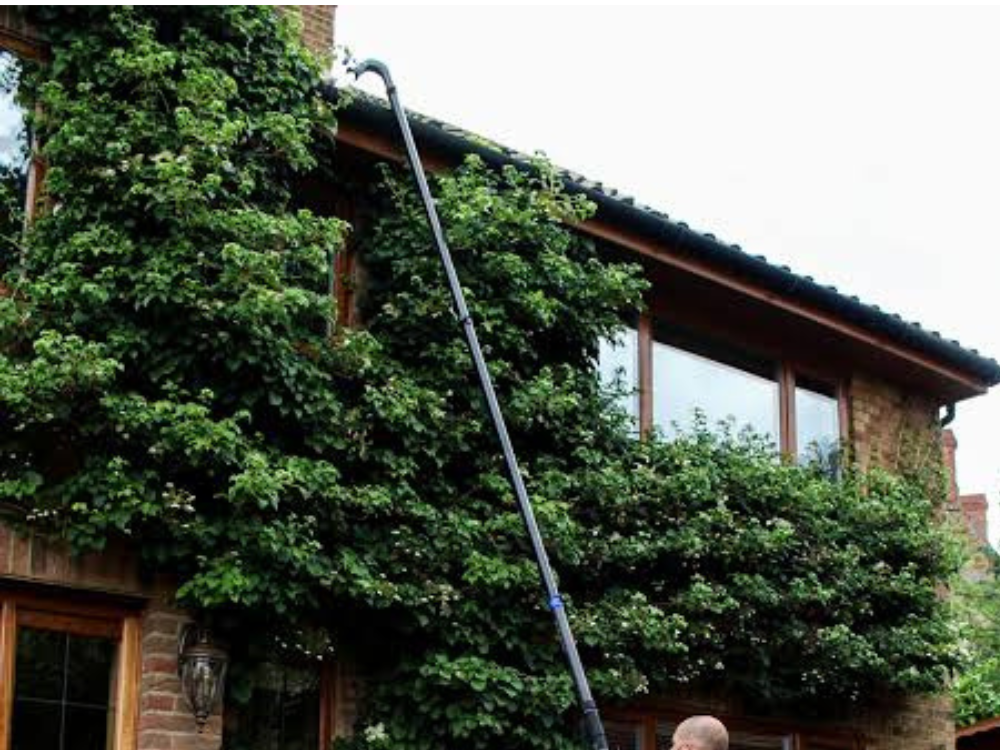 A gutter vacuum pole clearing the guttering of a house