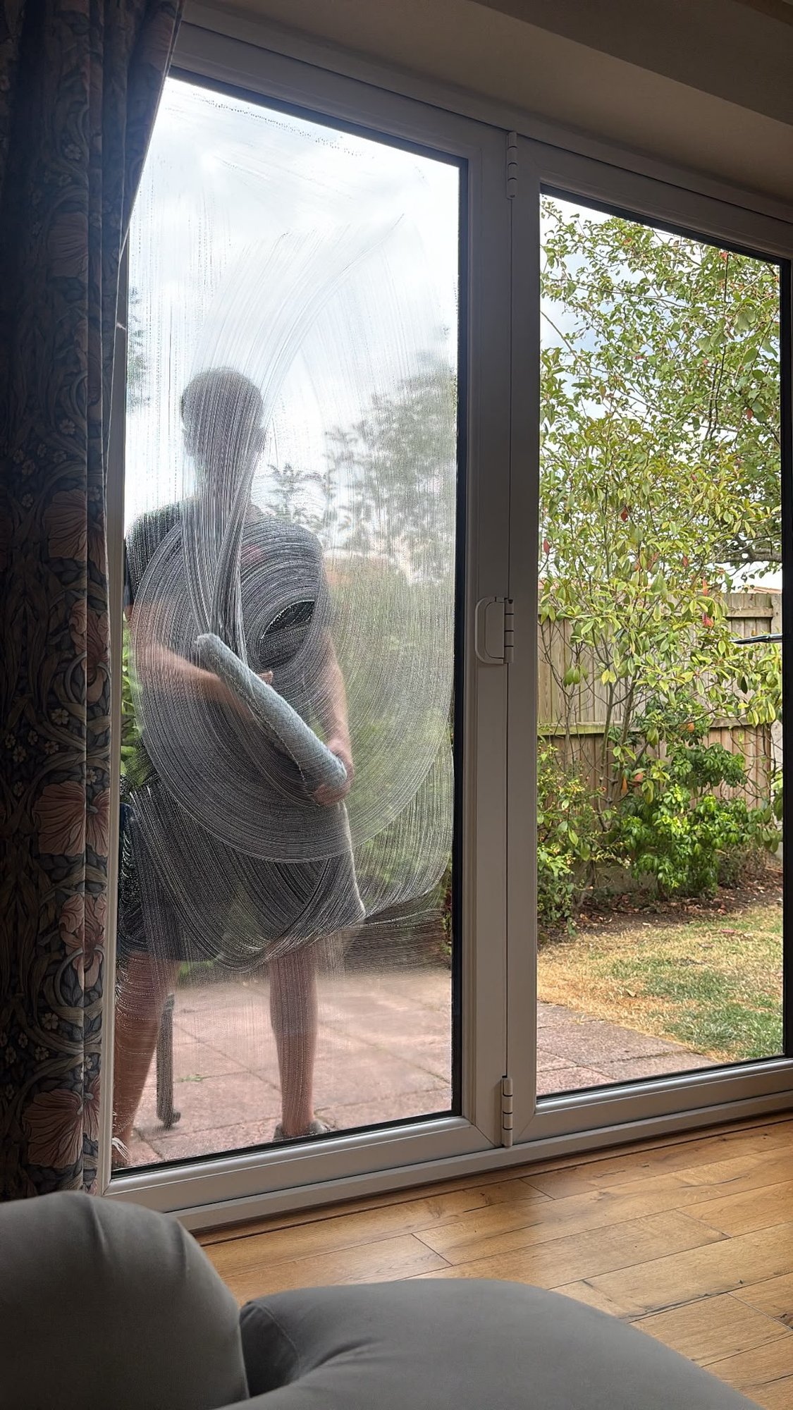 Patio doors being cleaned, seen from inside the room