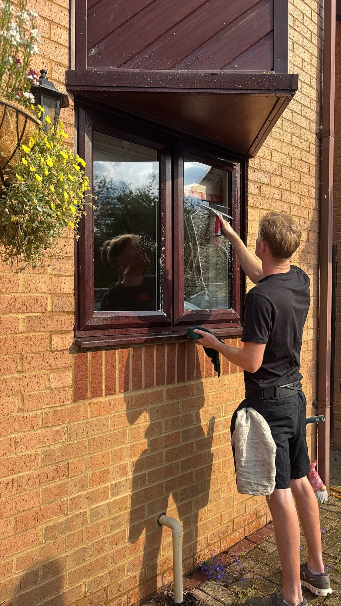 Squeegee mid-pull across soapy glass on a residential window